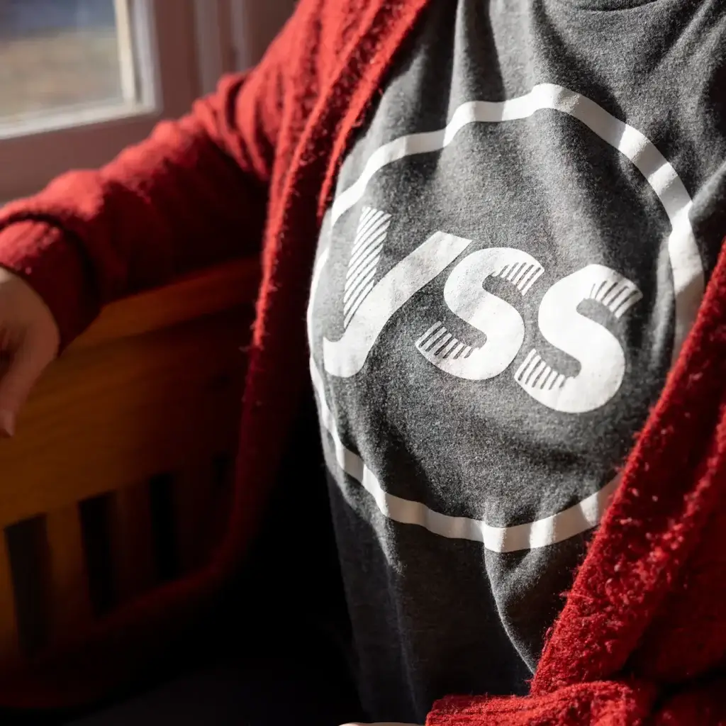 Close up of a woman's torso wearing a red sweater over a gray YSS shirt