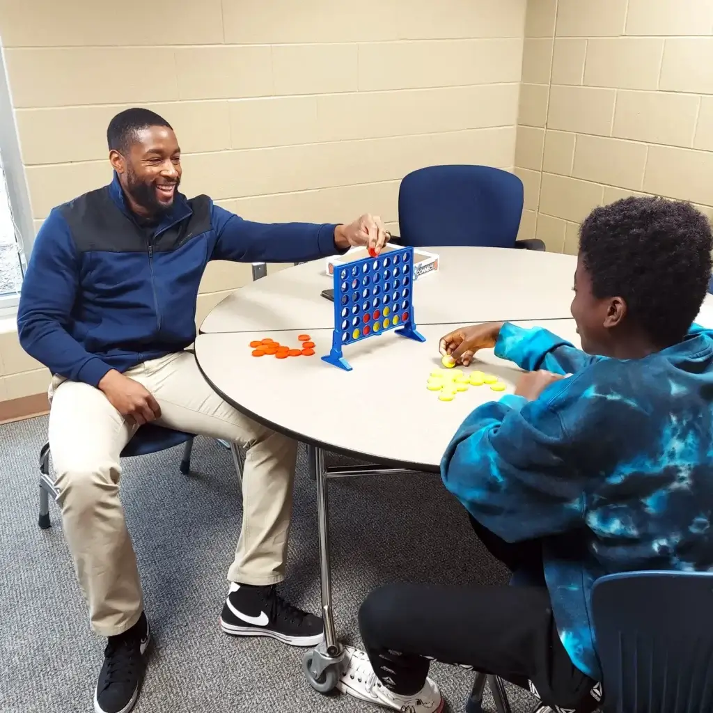 An adult and child playing a game of connect four.