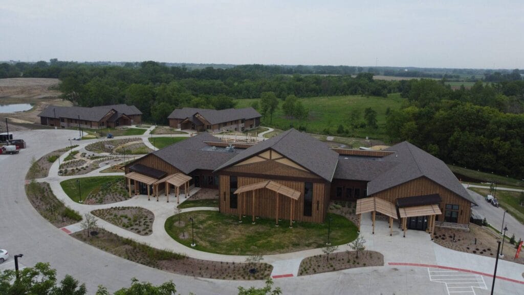 Aerial view of brown wood paneled buildings with curved sidewalks and landscaping.