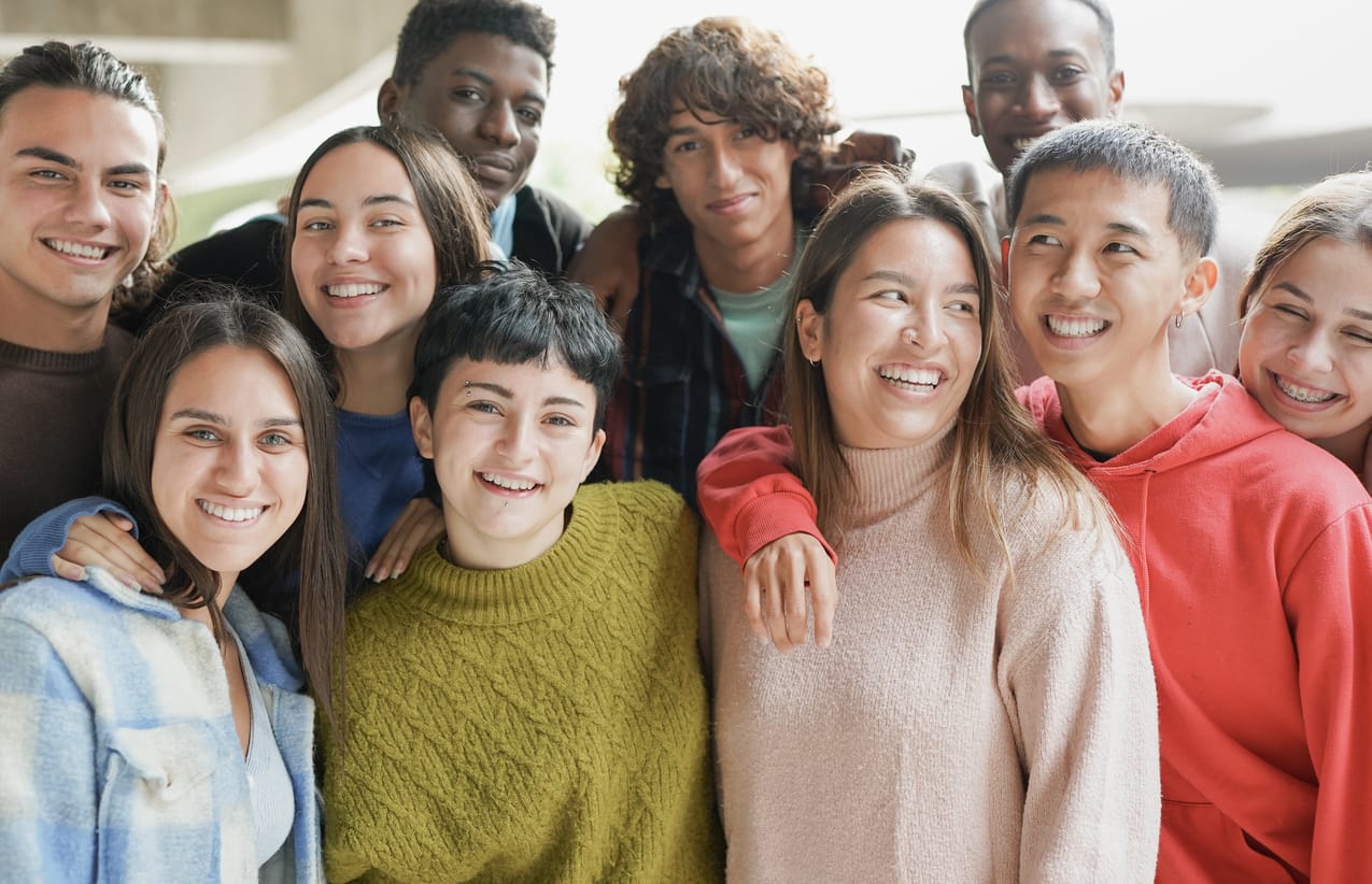 Diverse young students hugging each other outdoor of school building Young multiracial people having fun together